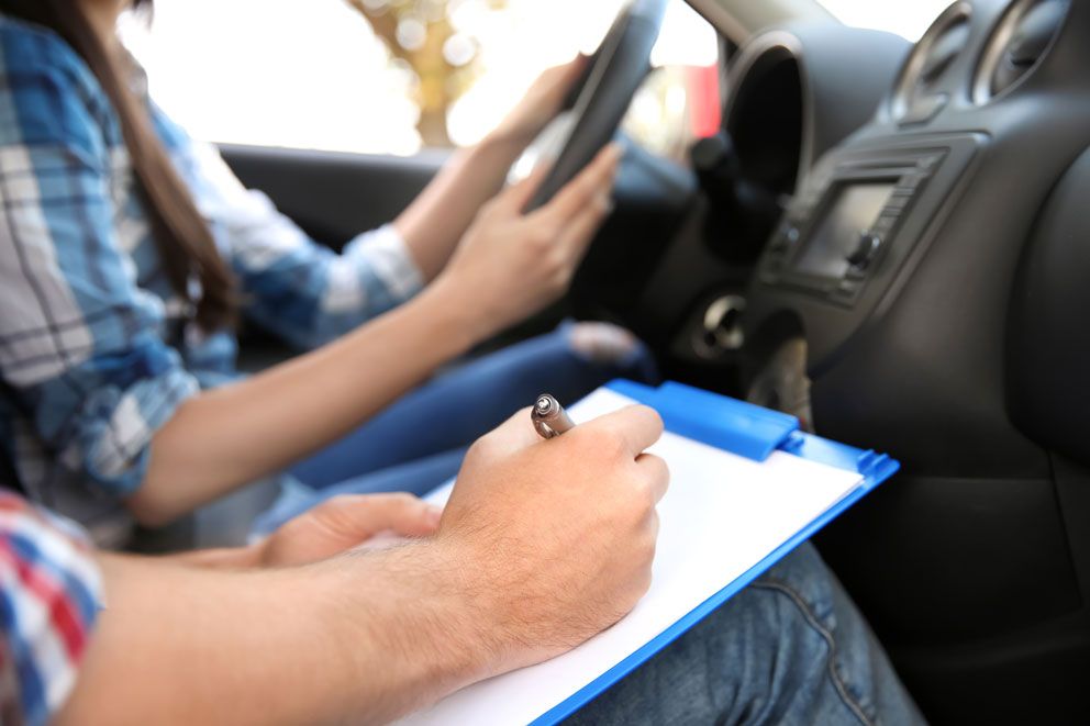 Der Prüfer notiert sich während der praktischen Fahrprüfung etwas